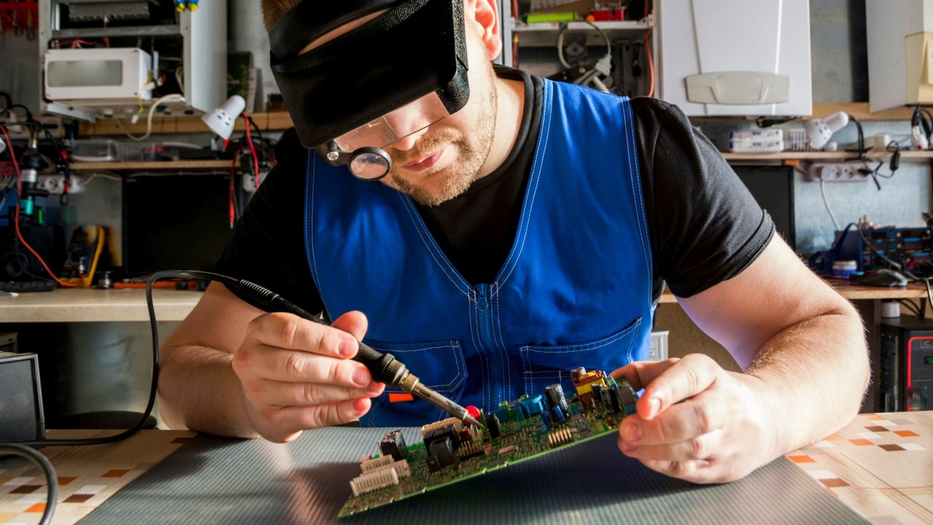 Man soldering/repairing circuit board. 