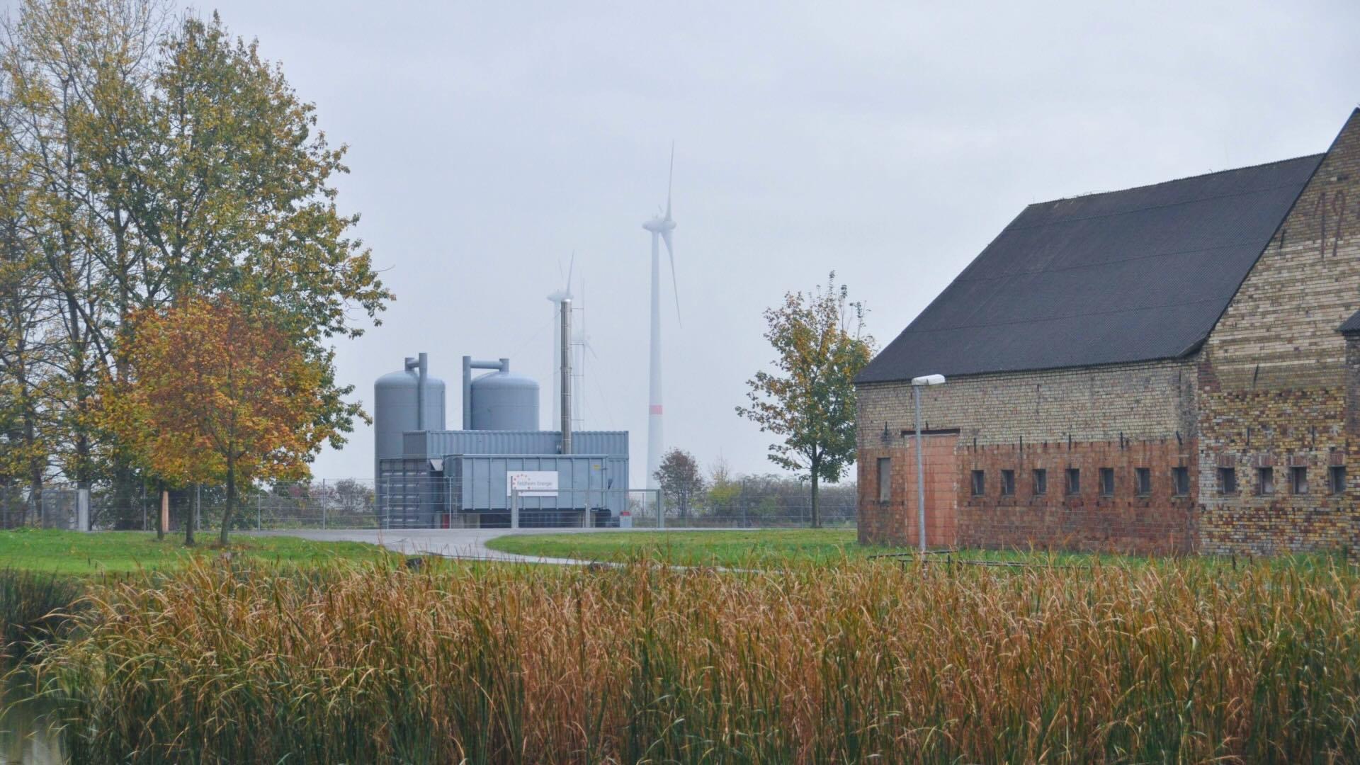 Feldheim, Germany. Wind turbines, heat exchanger, old town buildings, and trees. 