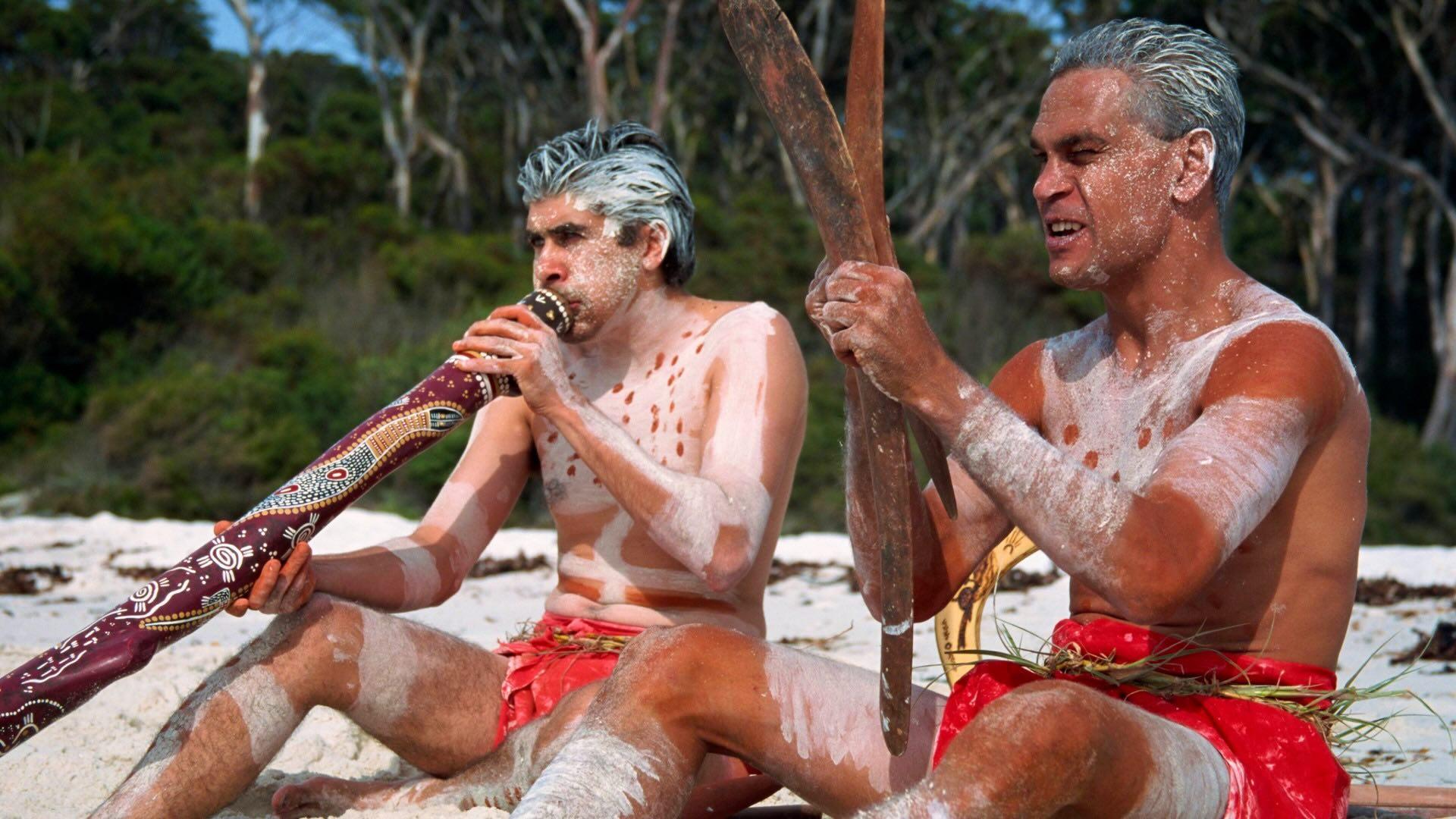 Two men with Aboriginal digeridoo and boomerang at Jervis Bay Australia D Harcourt Webster