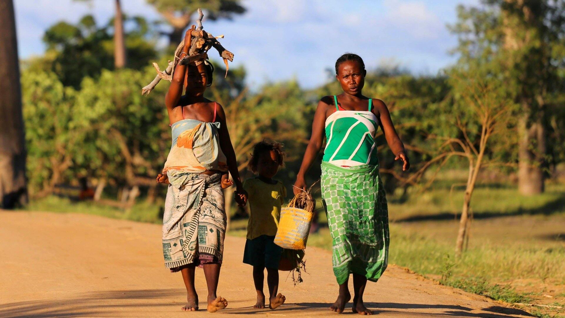 Two women and child walking outside. Madagascar.